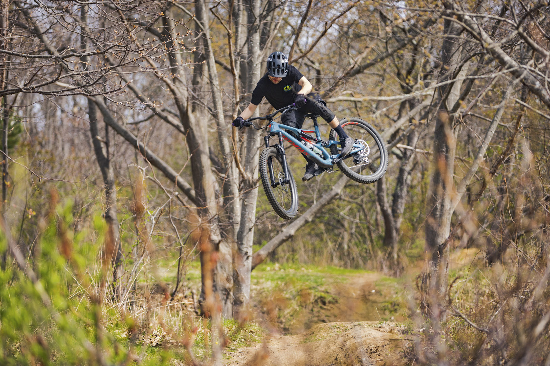 Mountain biker whipping a jump in the bare spring woods